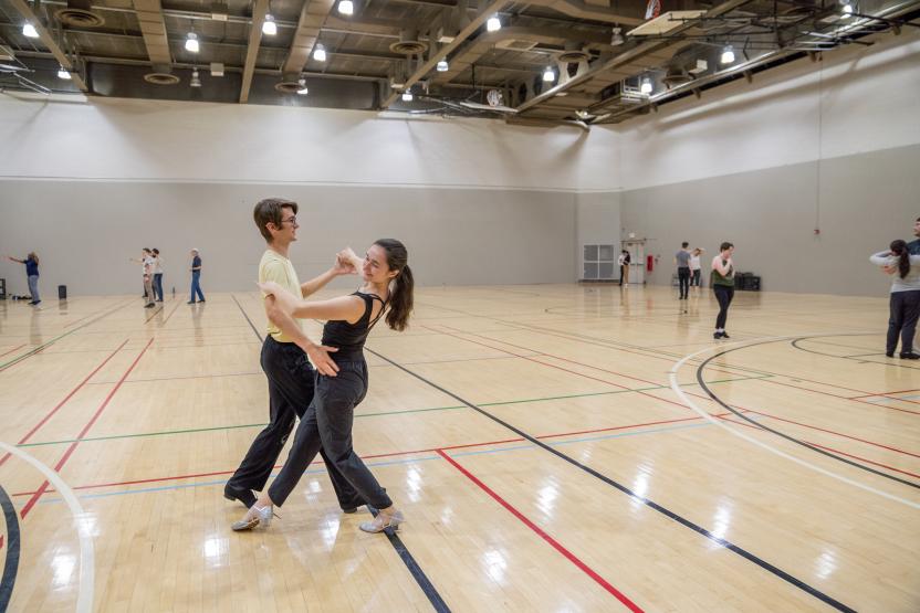 two ballroom dancers in a large gymnasium
