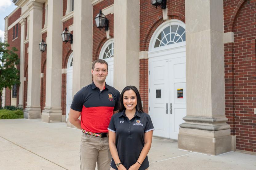 Two athletic trainers stand side by side in front of Ritchie Coliseum.