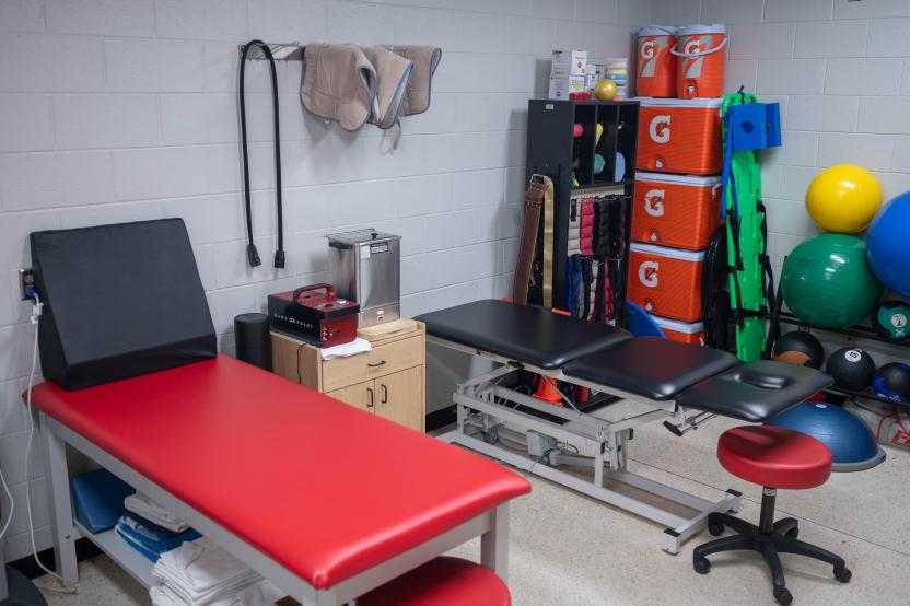 Two treatment tables are pictured within the athletic training clinic along with Gatorade coolers and physio balls in the background.