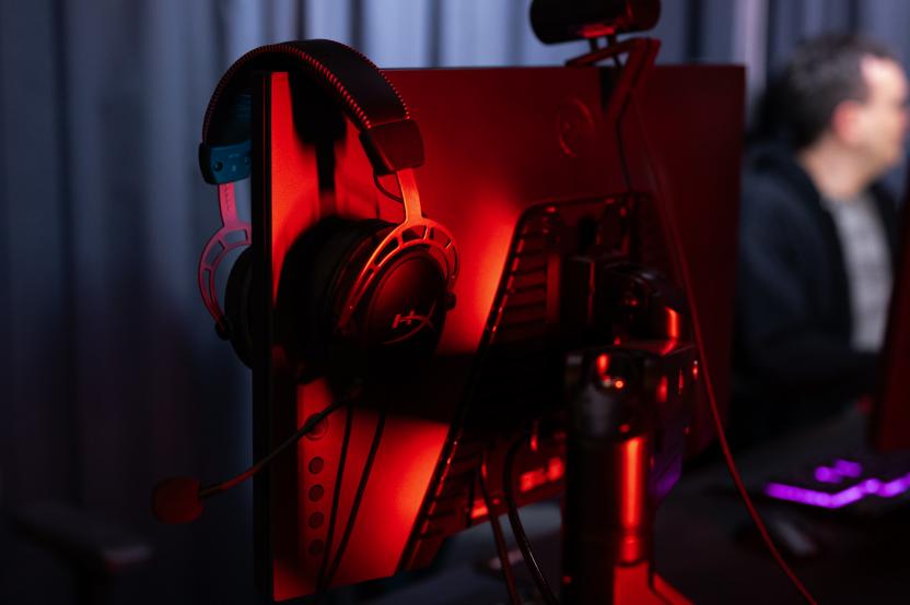 Illuminated backside of a computer monitor with a headset on the screen.