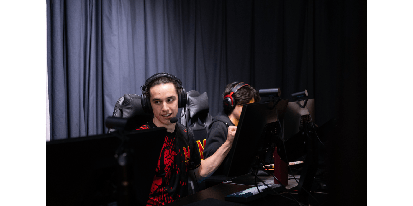 Terps Esports player fistbumping his teammates while they sit at their computers. 